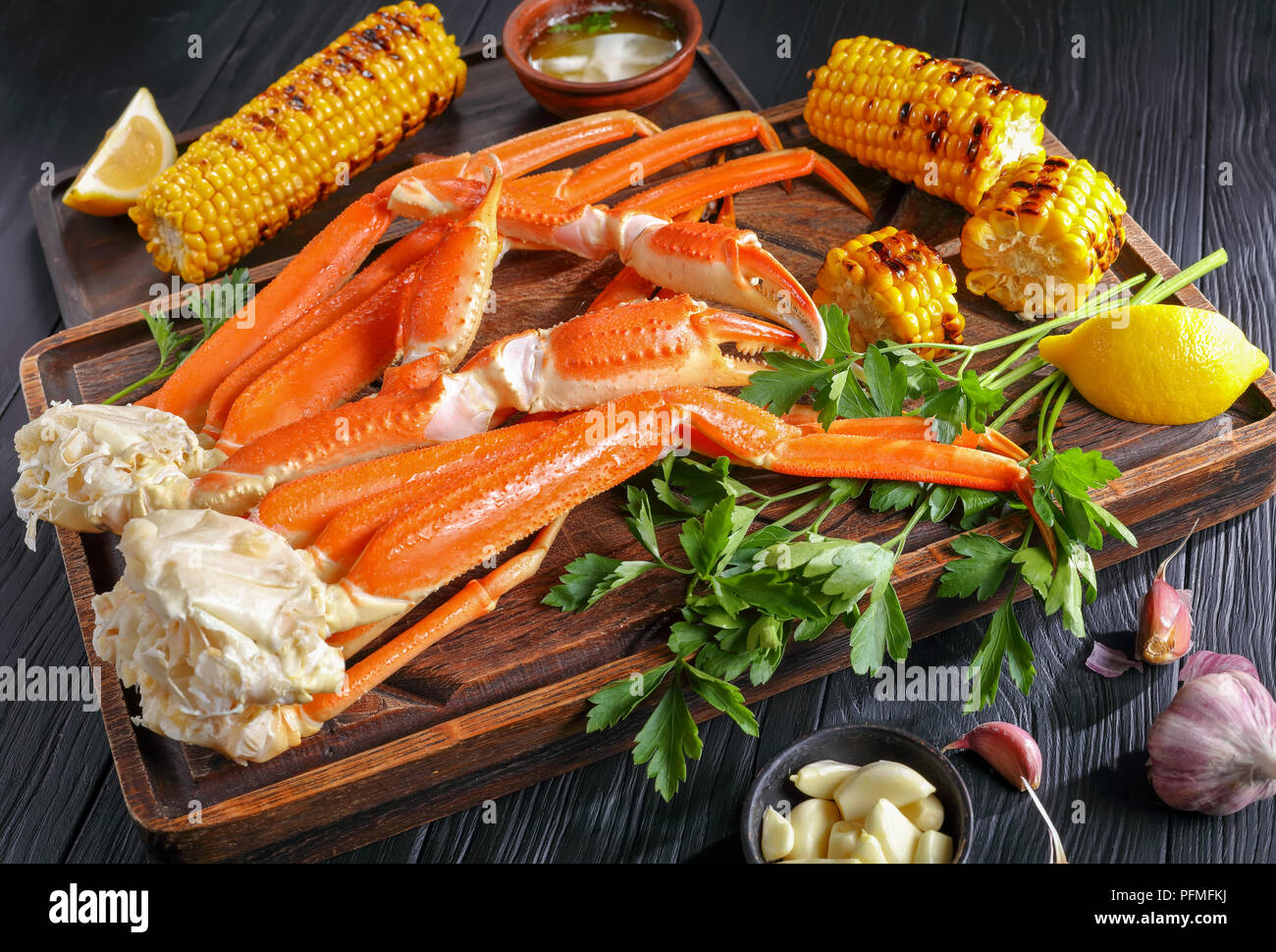 snow Crab legs served with melted butter in clay bowls, garlic cloves
