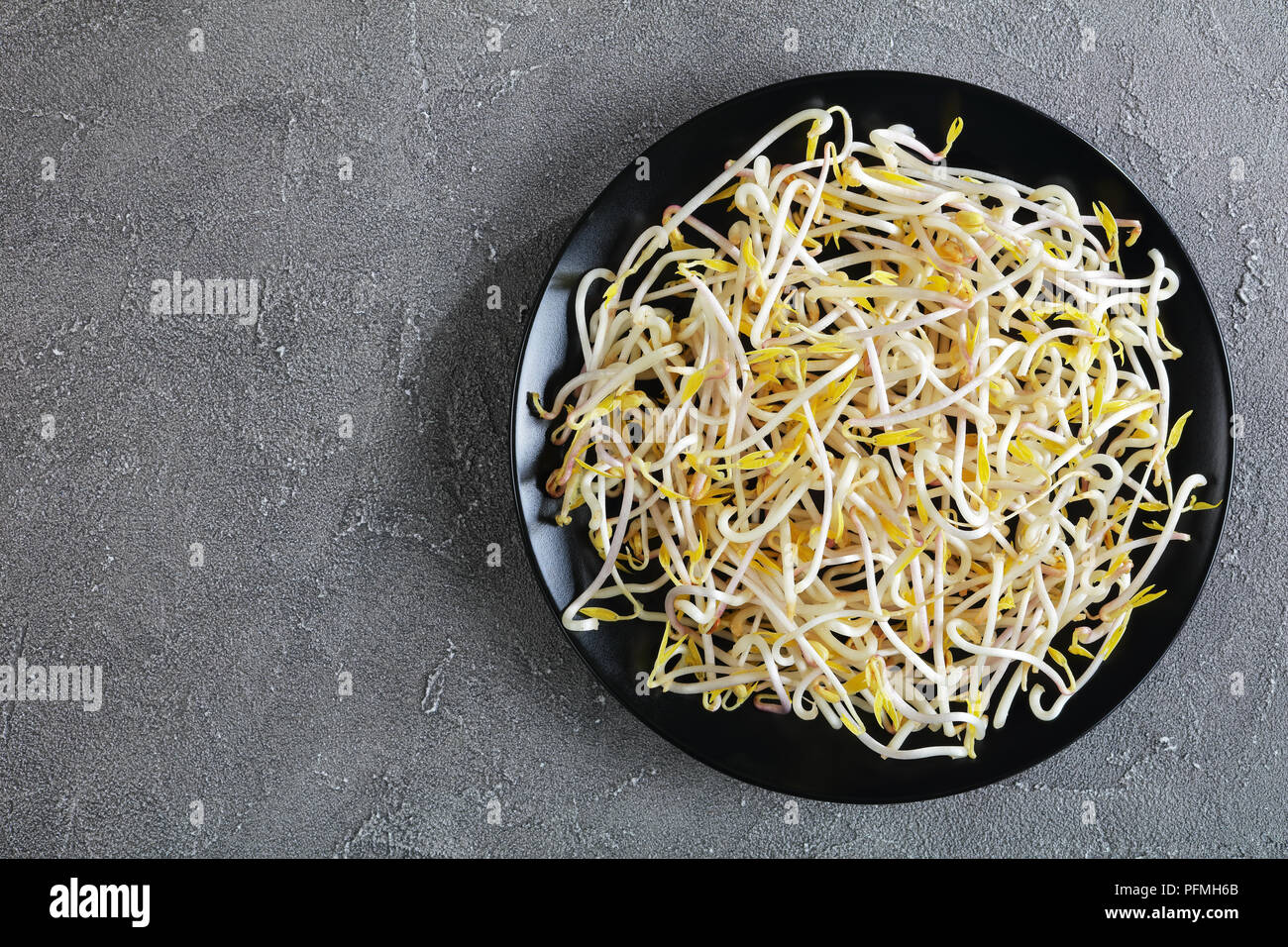 Fresh  mung Bean Sprouts on black plate on concrete background, major ingredient of asian cuisine, view form above Stock Photo