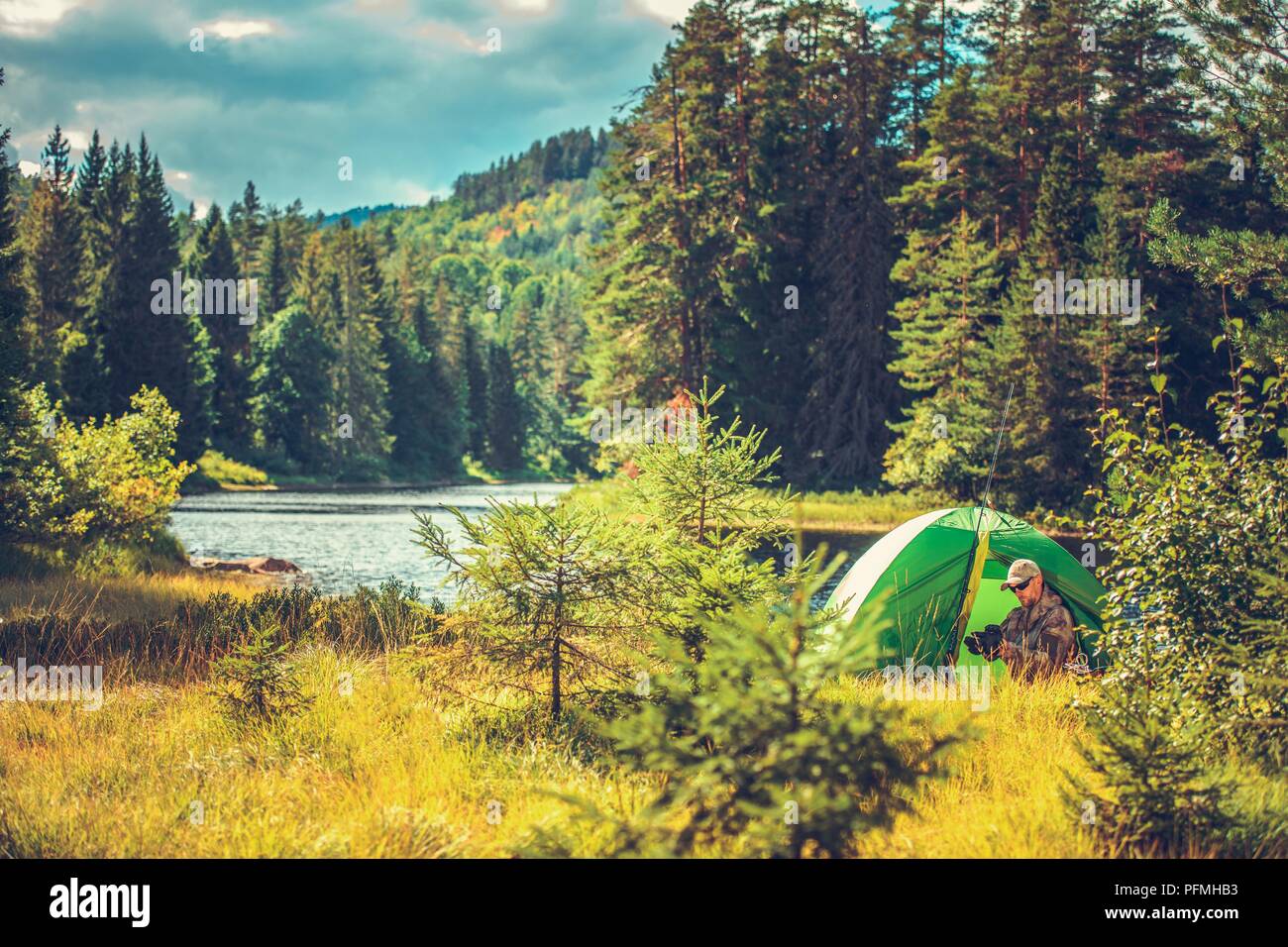 Survival Camping in the Wild. Caucasian Men in His 30s in a Tent Preparing His Equipment For the Fly Fishing Stock Photo