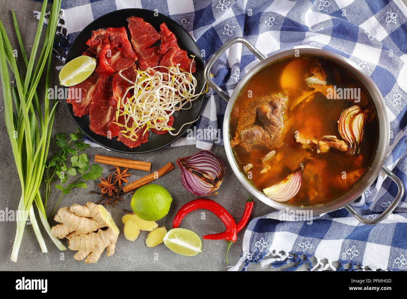 hot beef bone broth and other ingredients for classic Vietnamese soup Pho Bo, with raw beef, soy