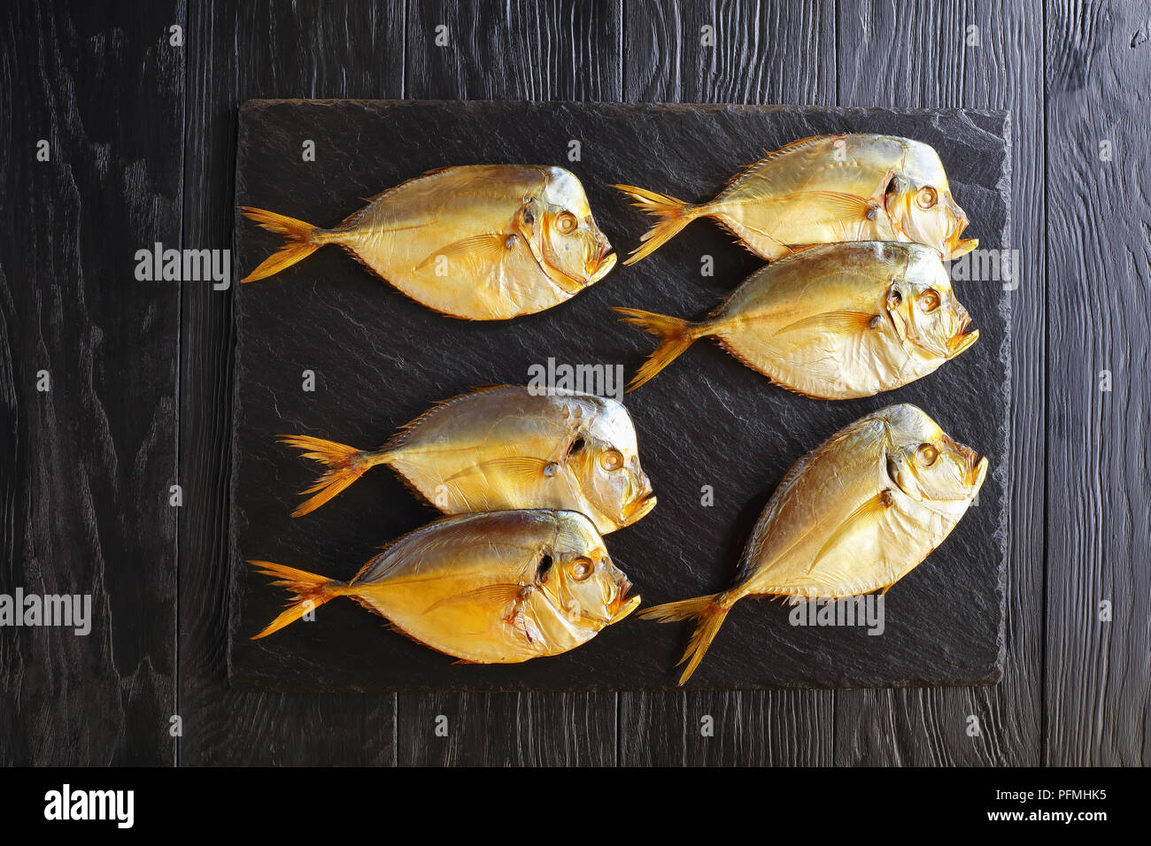 delicious cold smoked moonfish on black stone tray on black wooden table, view from above Stock Photo