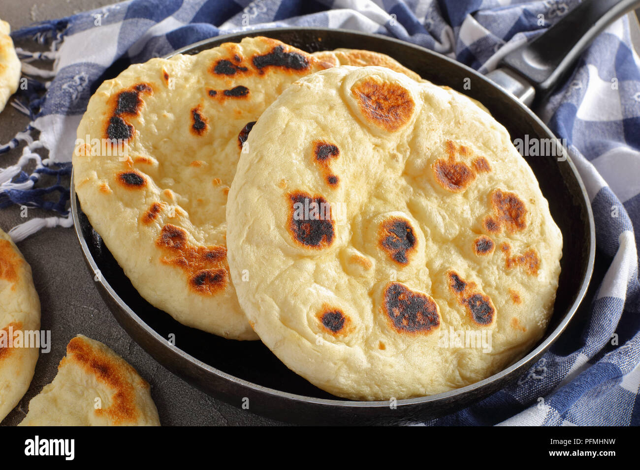 freshly pan fried pita bread in skillet with kitchen towel on concrete