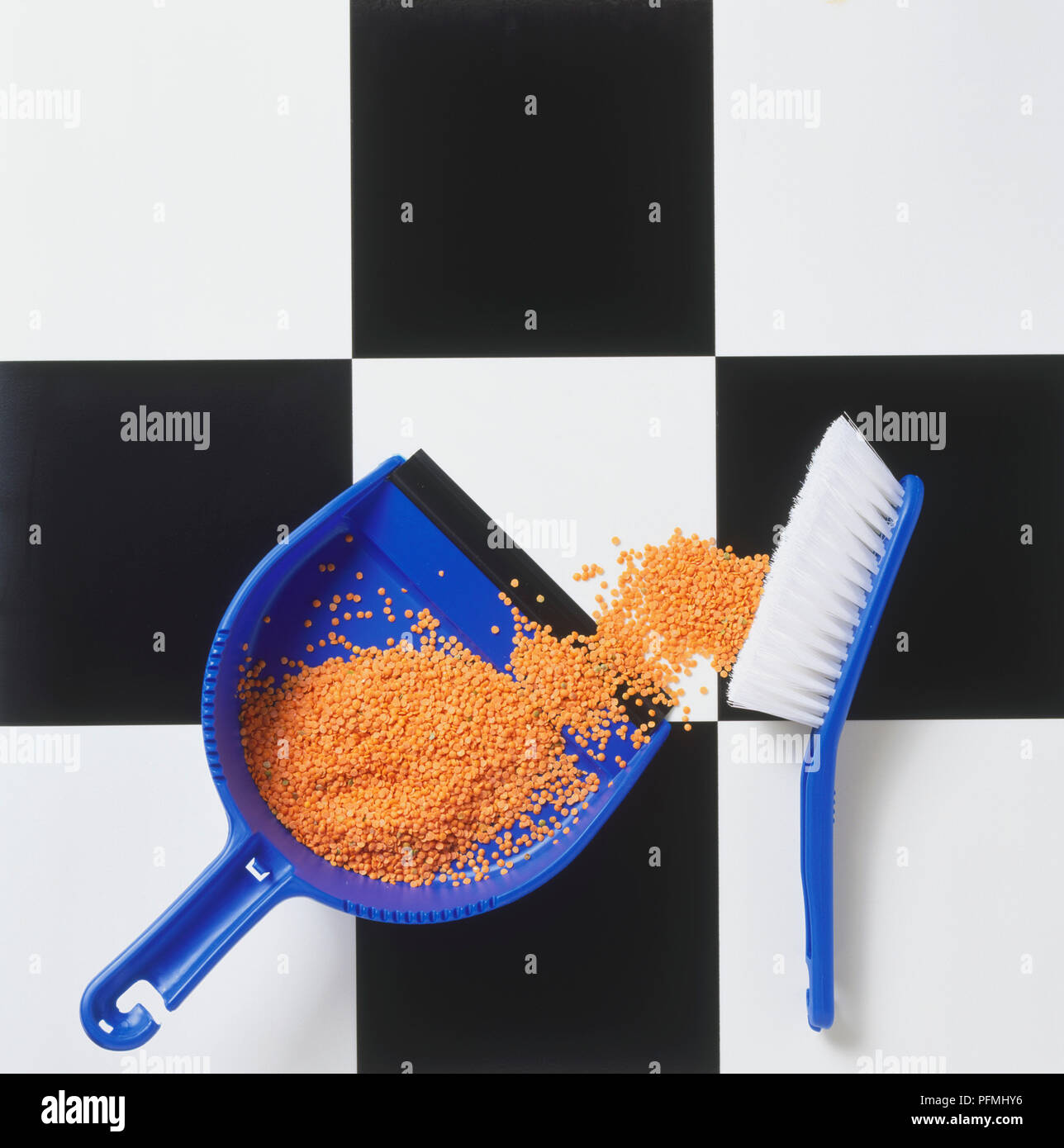 Vinyl kitchen floor with dustpan and brush containing lentils. Stock Photo