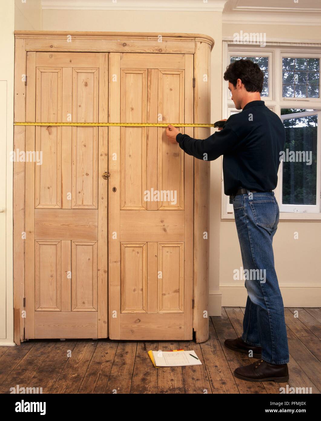Man using tape measure to measure dimensions and position of wooden
