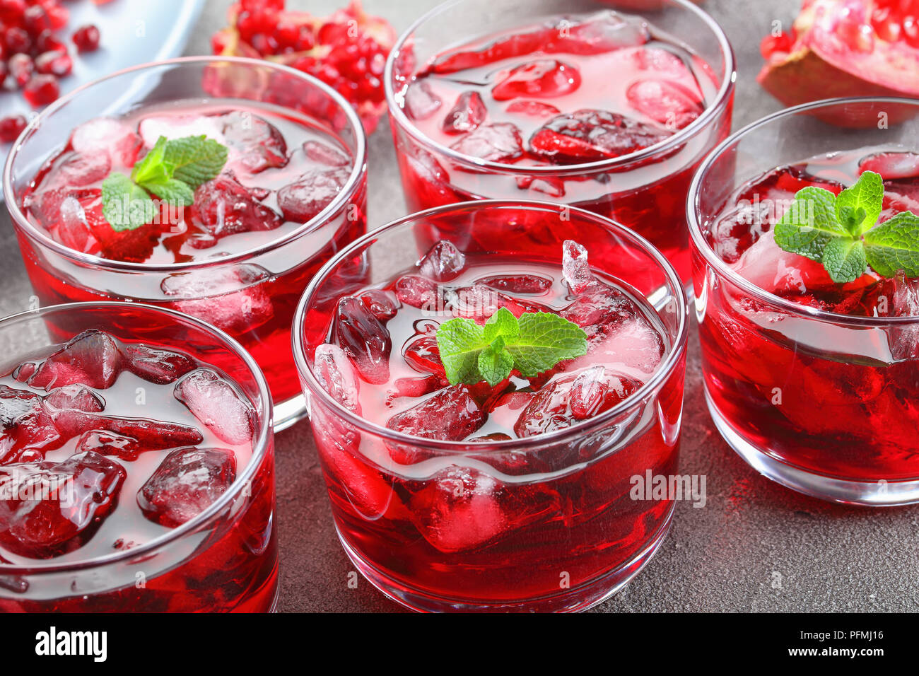 close-up of freshly made cold pomegranate juice with ice cubes and fresh mint in glass cups, horizontal view from above Stock Photo