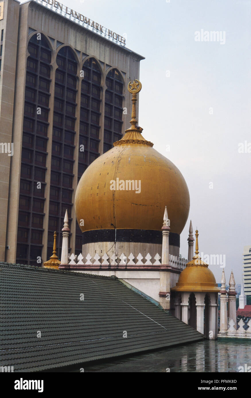 Singapore, Kampong Glam, Sultan Mosque, two gold-coloured domes with pointed pinnacles and Islamic symbol, Arabesque stylings with Moorish overtones, modern high-rise in background creating strong architectural contrast. Stock Photo