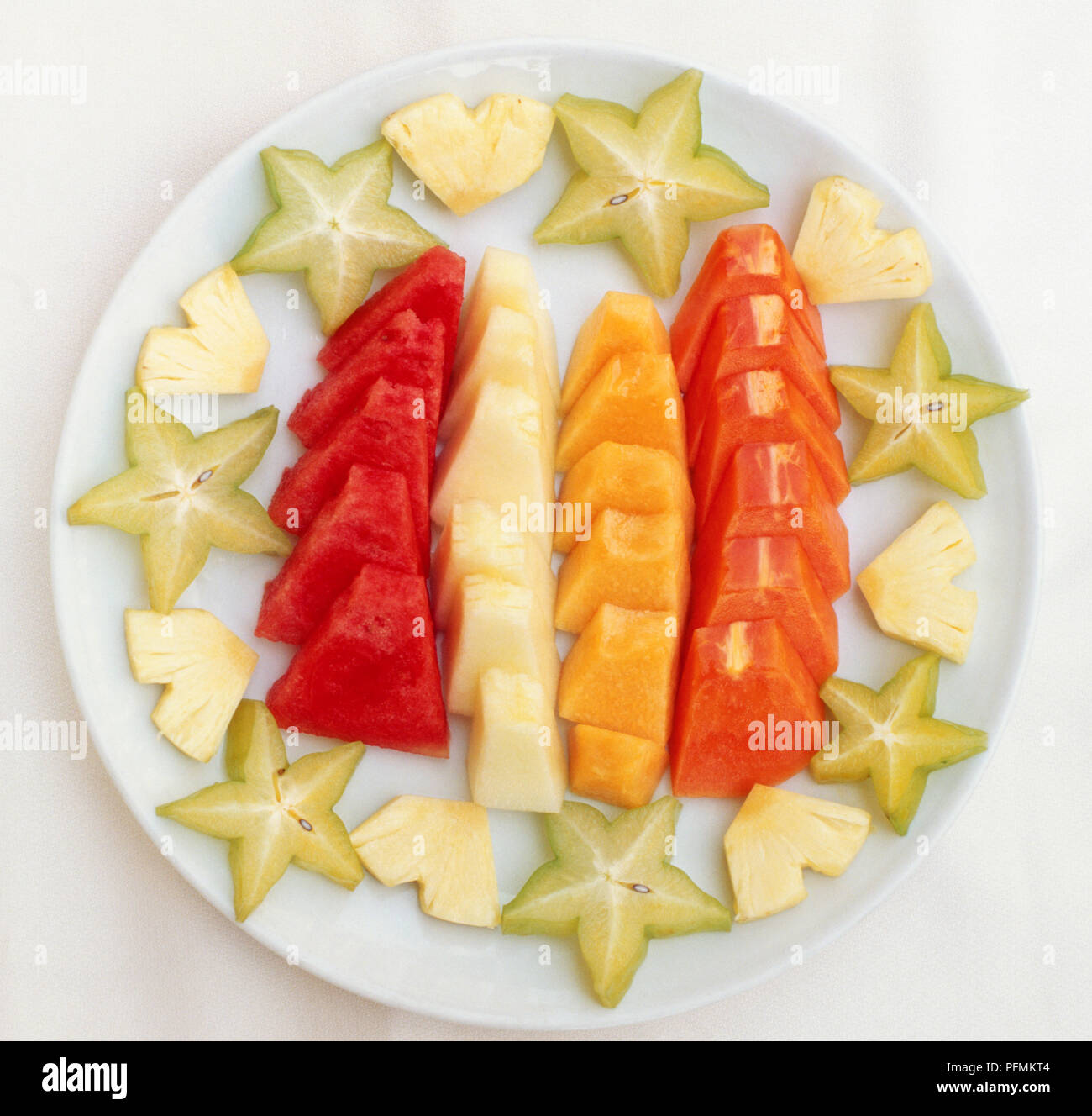 Dish of brightly coloured sliced fruits; pineapple, starfruit, papaya, rock melon, honeydew melon, and watermelon, popularly served in Singapore. Stock Photo