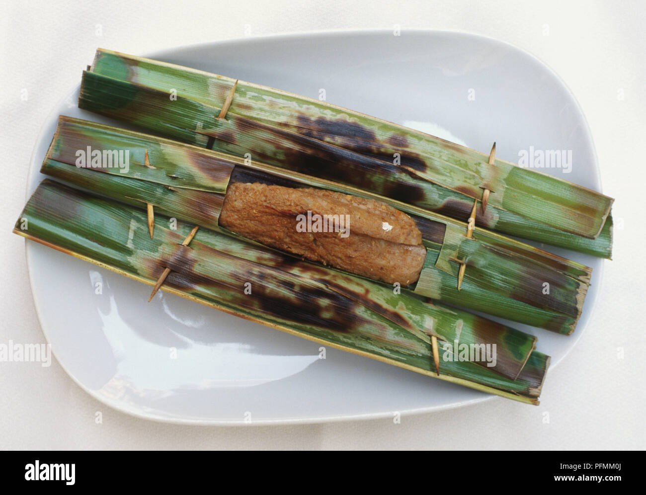 Malay Cuisine Otak Otak Fish Paste Wrapped In Coconut Leaf Section Of Leaf Removed Revealing Paste Small Wooden Sticks Securing Leaves Stock Photo Alamy