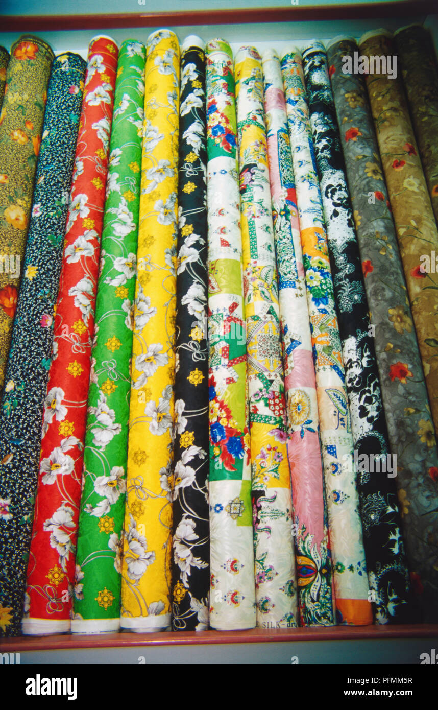 Singapore, traditional textiles rolled around cardboard rolls, vivid colours and patterns including flowers. Stock Photo