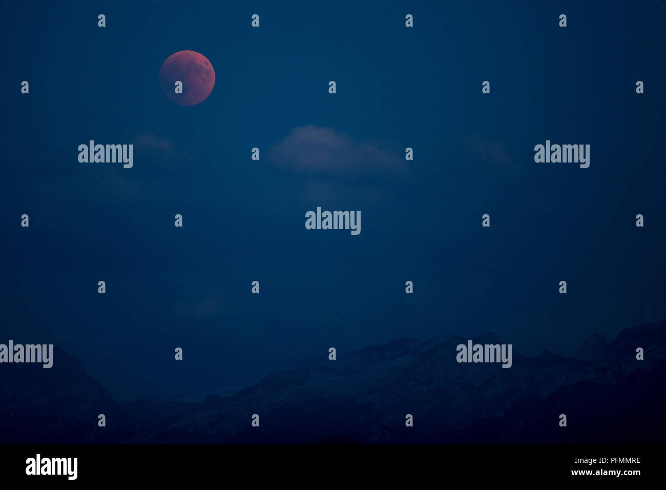Bloodmoon, total lunar eclipse over mountain range, Immensee, Switzerland Stock Photo
