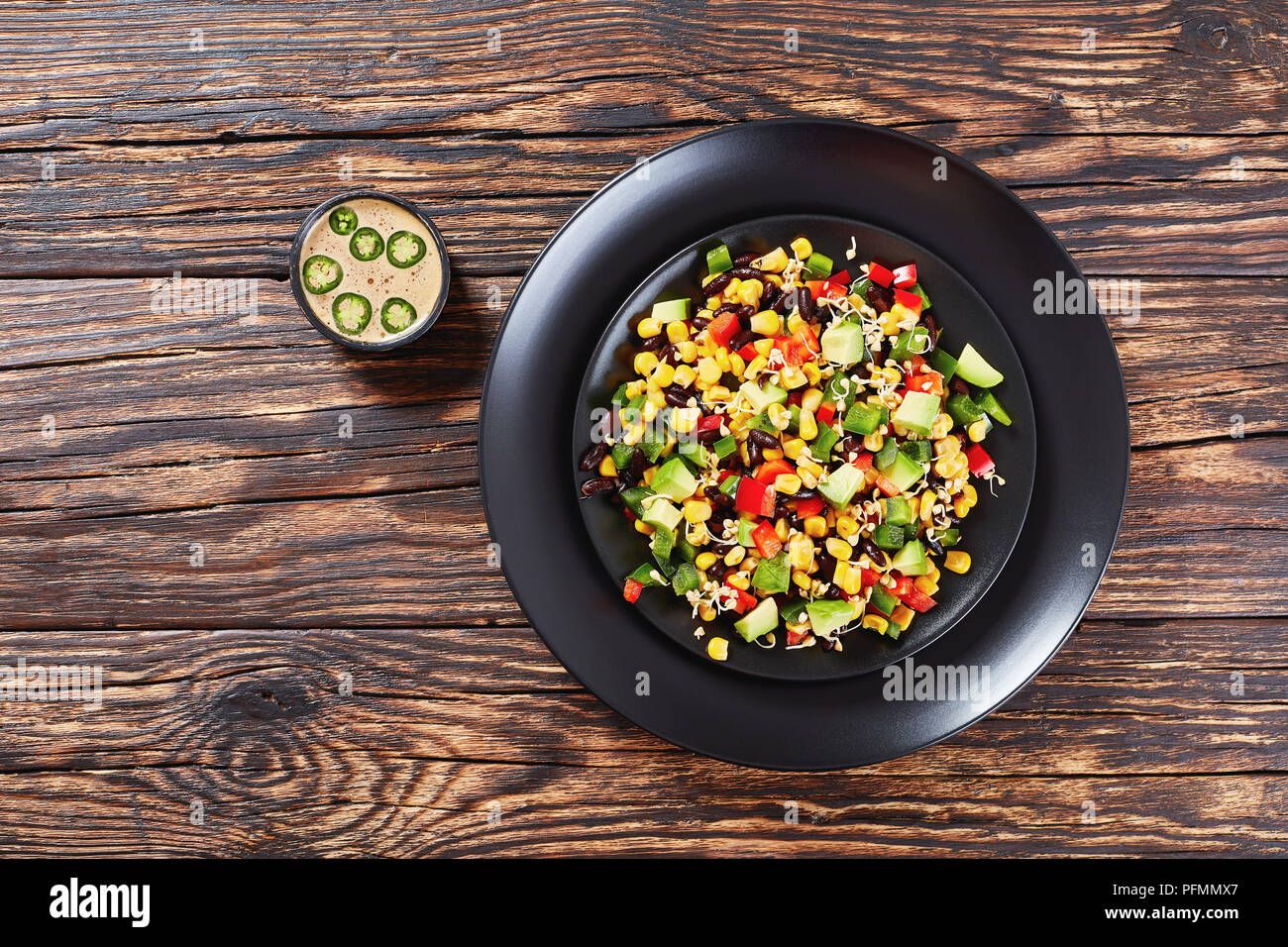 delicious fresh colorful mexican style salad with avocado, black beans, canned corn, buckwheat sprouts, diced red and green pepper served on black pla Stock Photo