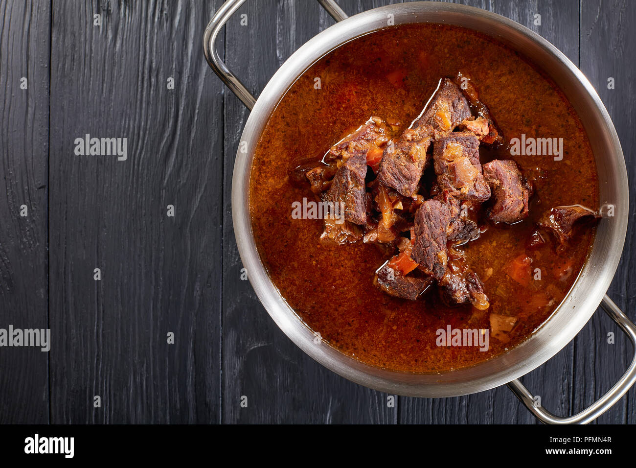 homemade hot Czech beef goulash in a stainless pan on black wooden table, view from above, close-up Stock Photo