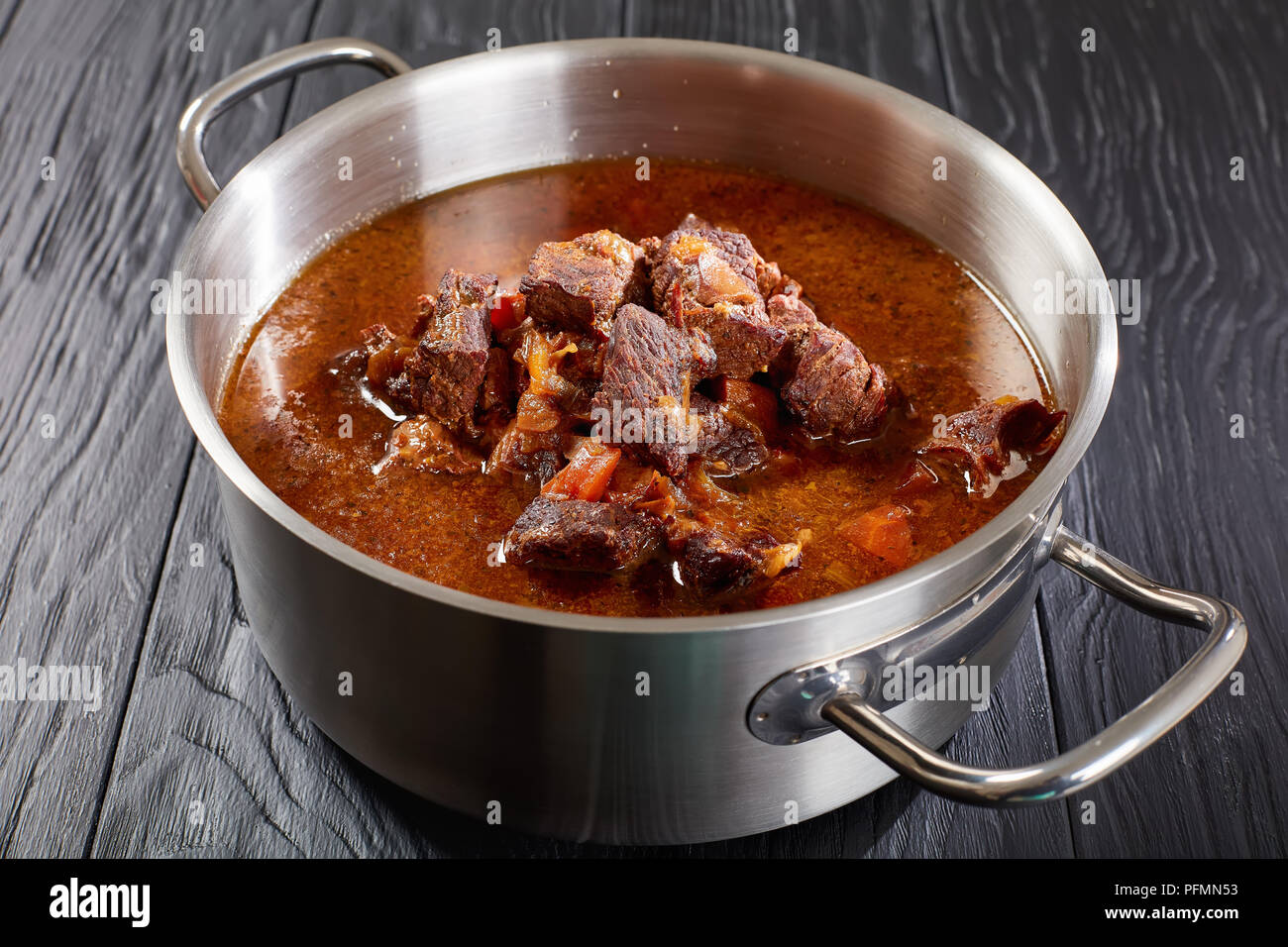 close-up of delicious homemade hot traditional Czech beef goulash in a stainless pan on black wooden table, view from above Stock Photo