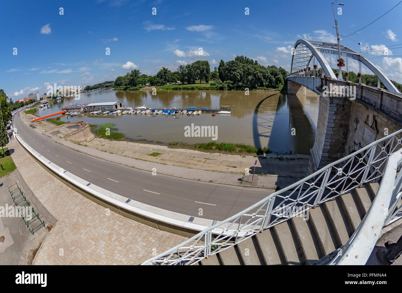 The embankment of Tisza river and the famous  Downtown Bridge also known as Belvarosi hid bridge,and the port with boats at Szeged,Hungary. Stock Photo