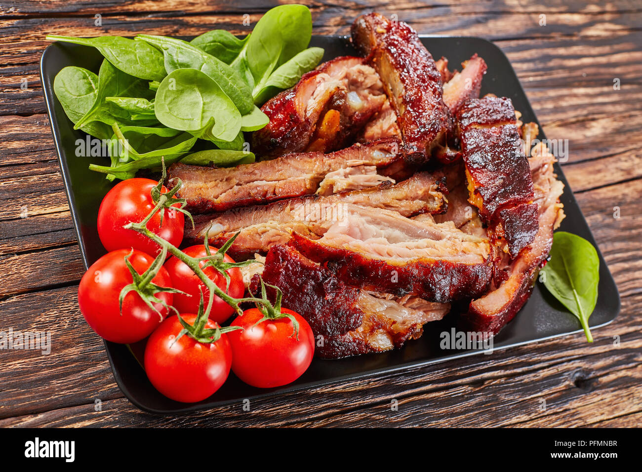 delicious sliced BBQ ribs with fresh green spinach ad cherry tomatoes