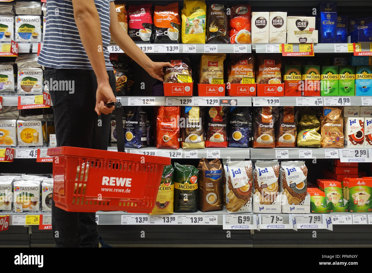 Shopper with shopping basket in a REWE supermarket Stock Photo