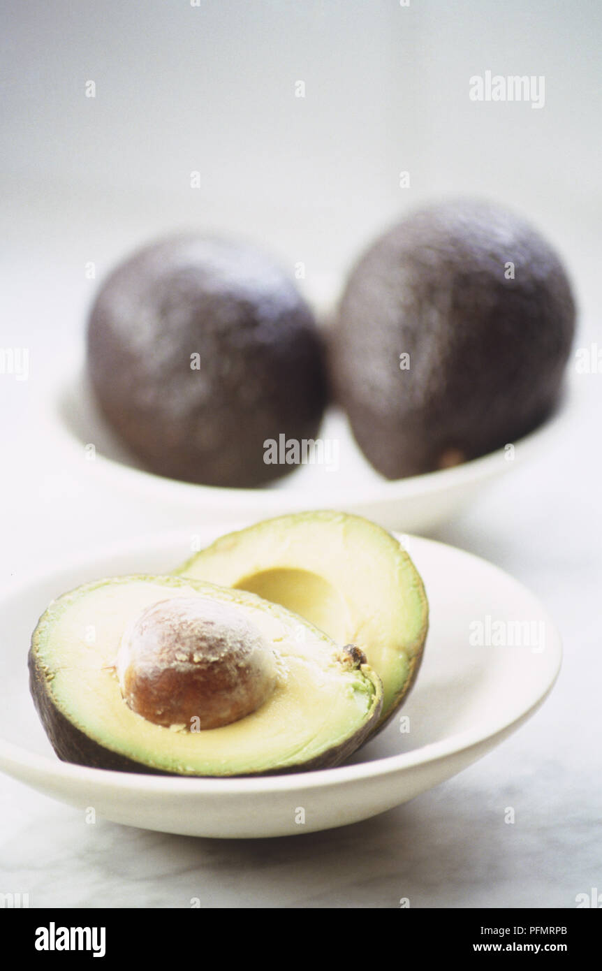 Halved and two whole avocados, side view Stock Photo Alamy