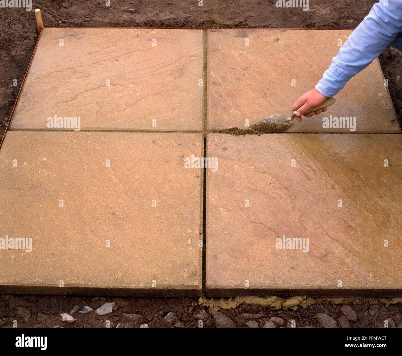 Man using to trowel to fill gaps in paving stones with mortar Stock Photo Alamy