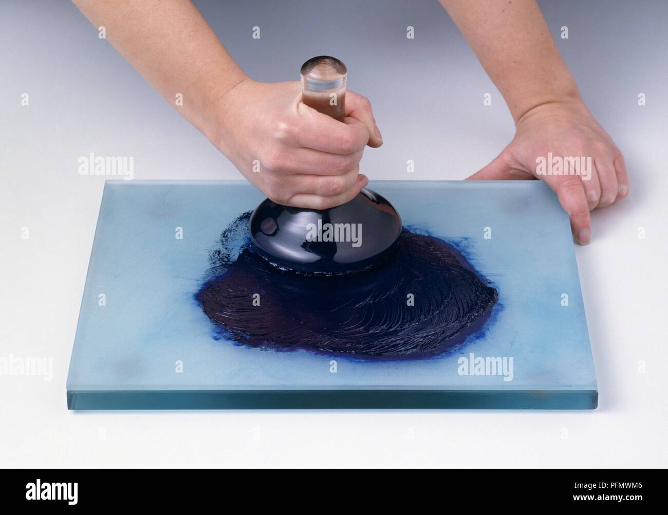 Using glass muller to grind ultramarine pigment and oil on slab Stock Photo  - Alamy