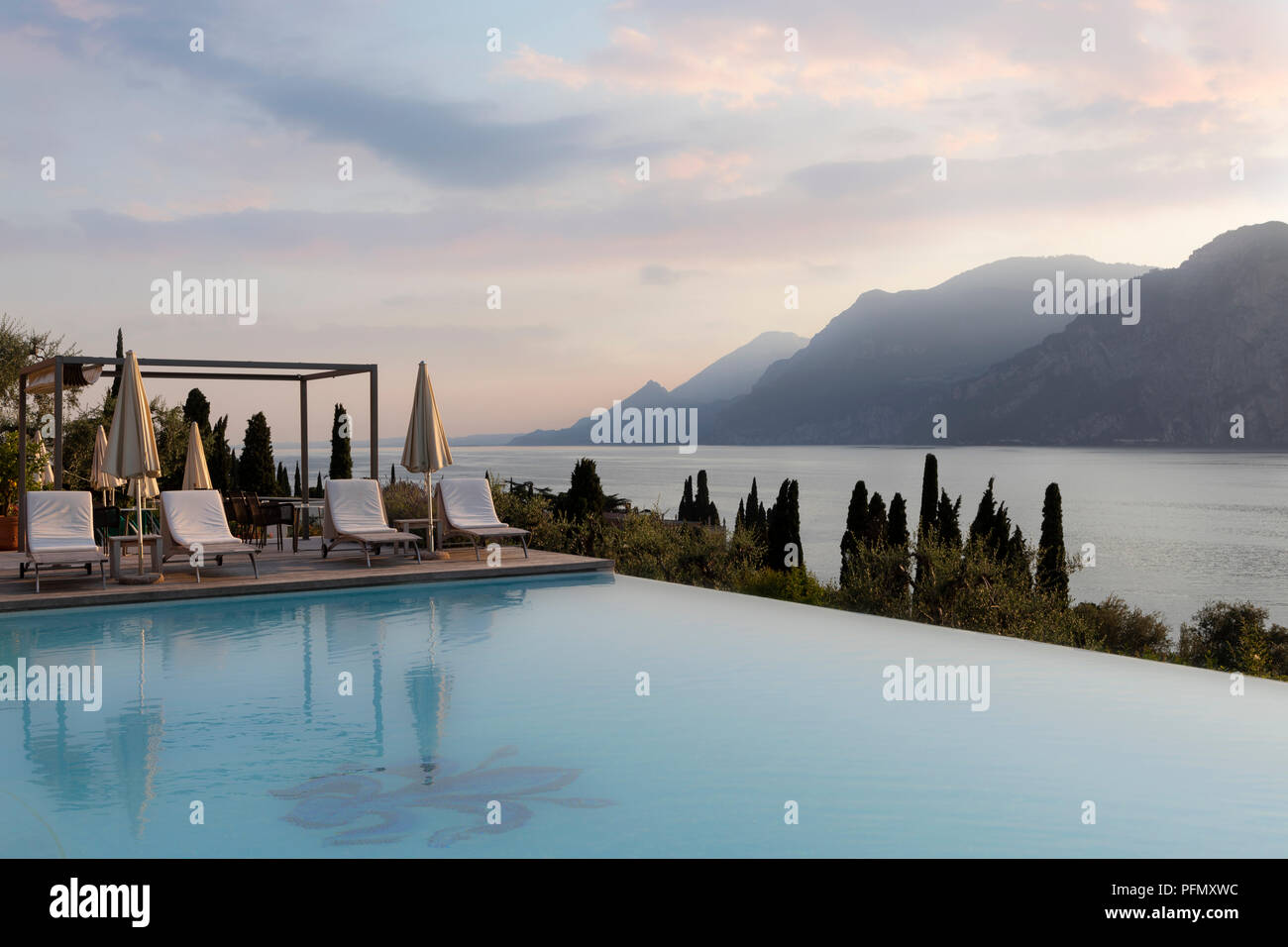 outdoor swimming pool at luxury hotel at sunset with lake and mountains Stock Photo