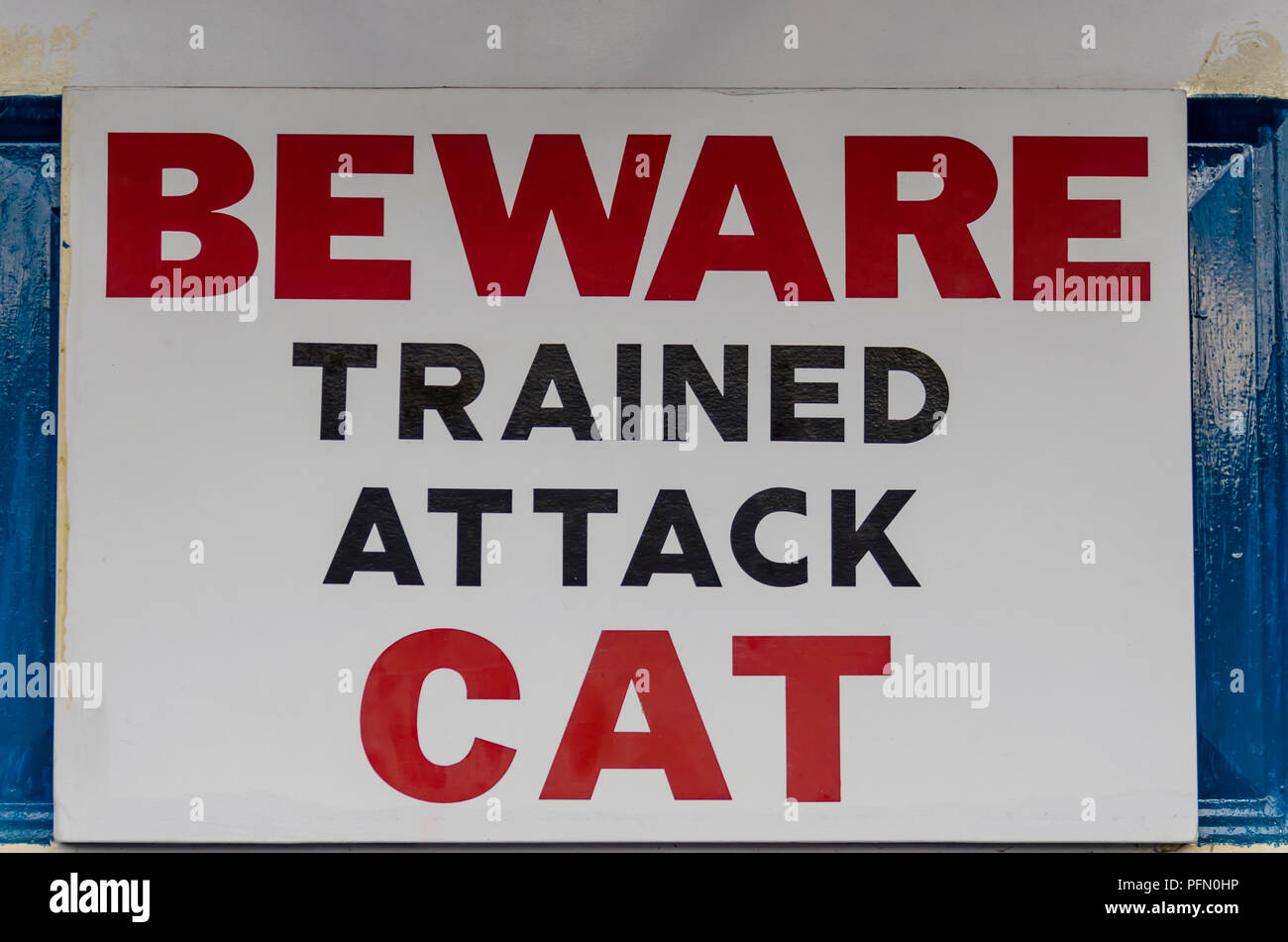 billboard warning, on the old door. Red and black letters on a white background. Carefully trained for attack cat. Stock Photo
