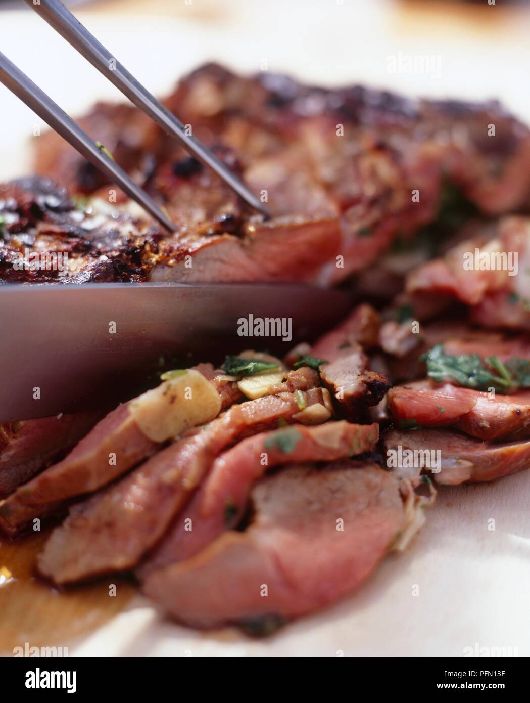 Carving grilled, butterflied leg of lamb persillade, close-up Stock ...