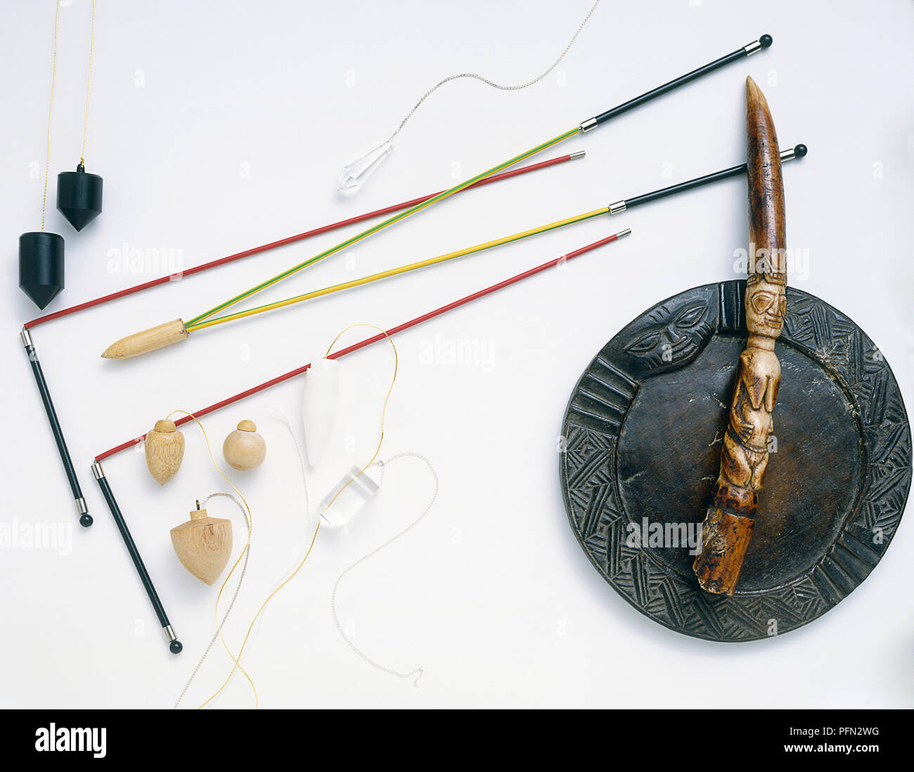 Witchcraft and fortune-telling paraphernalia, including pendulums, dowsing rod, and a divination tapper and bowl from Nigeria, view from above Stock Photo