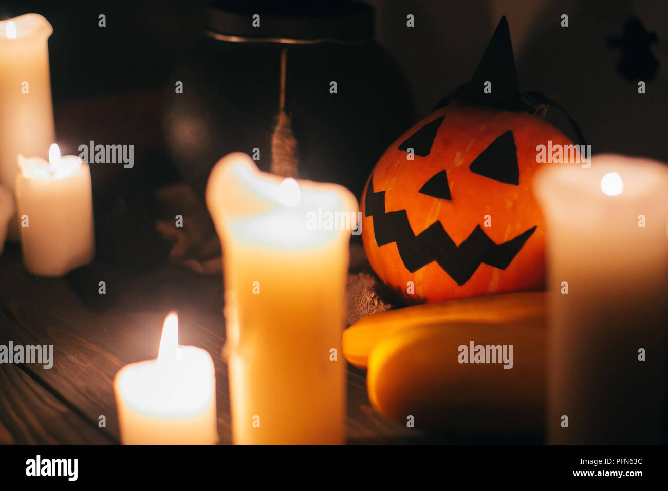 jack o lantern pumpkin with candles, bowl, witch broom and bats, ghosts on background in dark spooky room. Happy Halloween concept. fall halloween ima Stock Photo