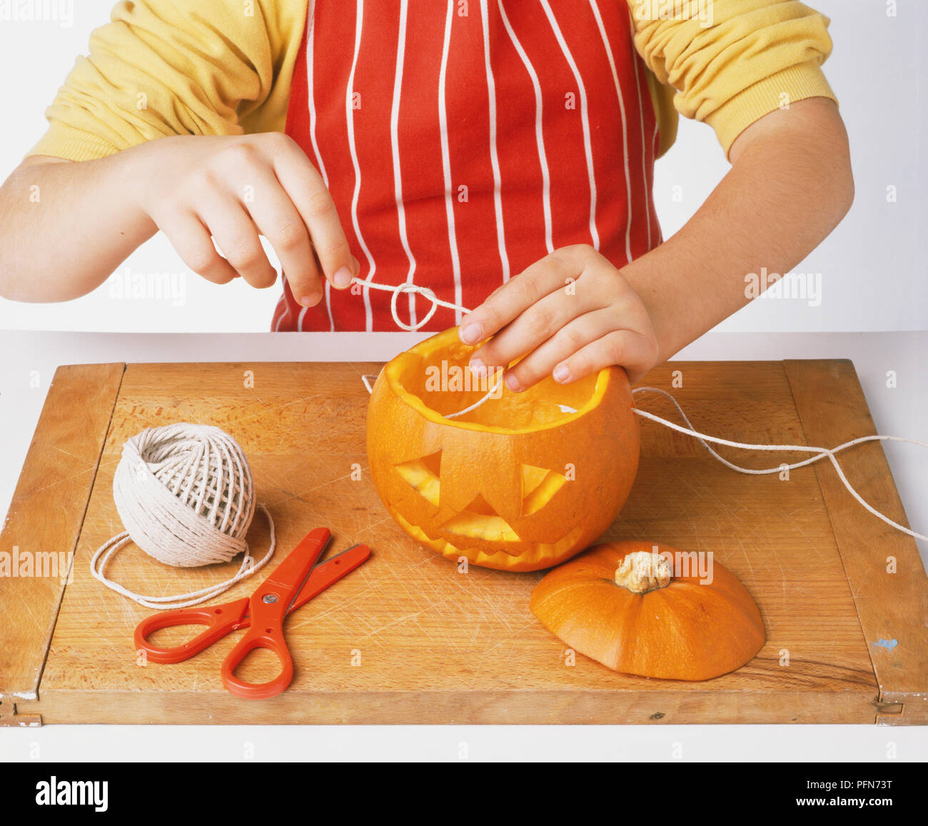 Child threading string through carved pumpkin Stock Photo - Alamy