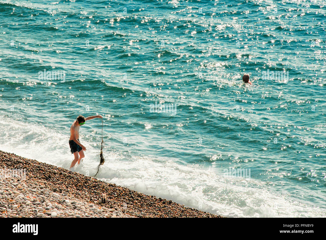 Chesil Beach. 21st August 2018. Two males enjoy swimming off Chesil Beach,  Portland, in Dorset, the