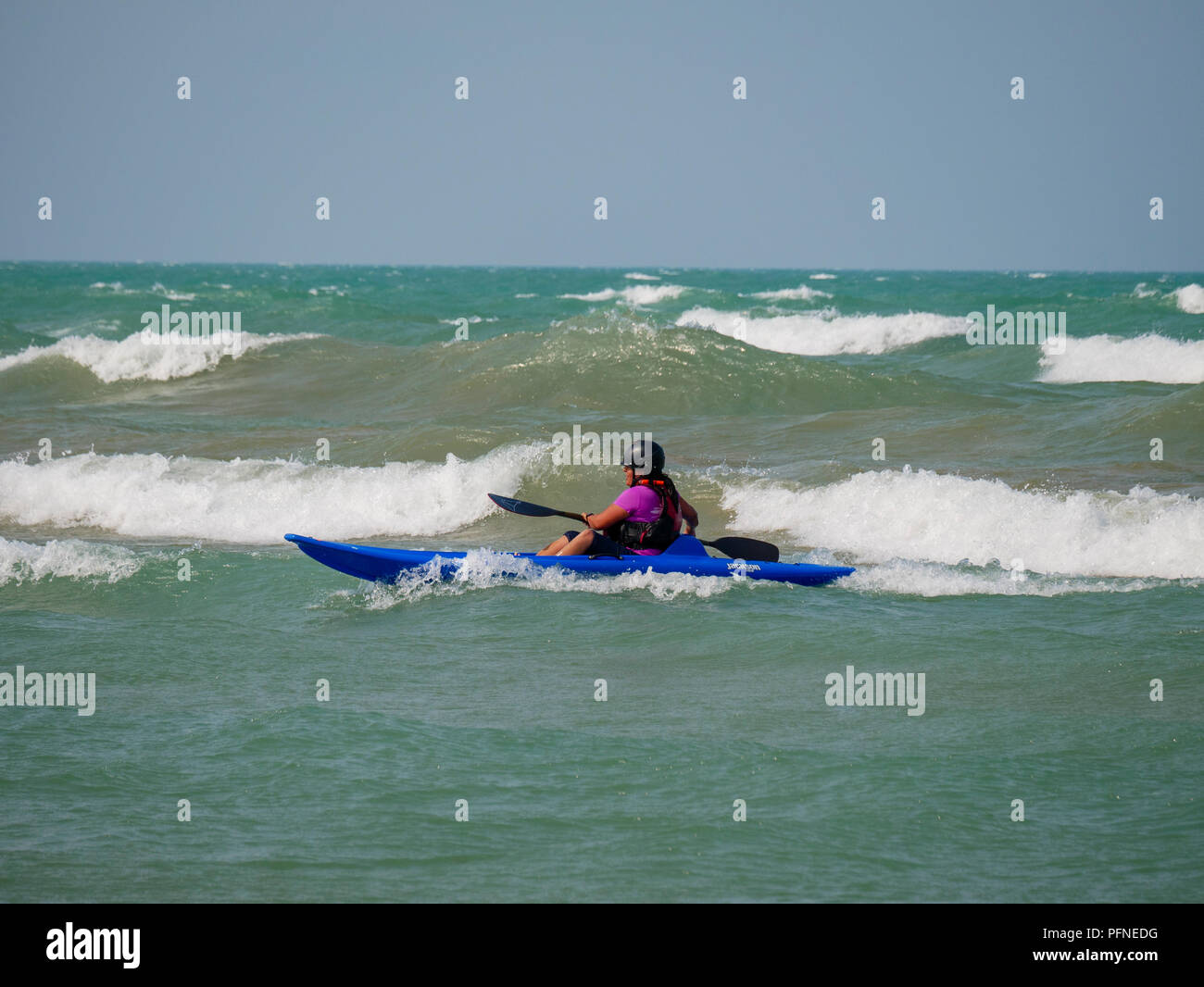 Chicago, Illinois, USA. 21st August 2018. A kayaker braves the surf at Montrose Beach. Stiff northeast winds whipped up surf on Lake Michigan, bringing out kayakers, kite surfers and wave watchers. Credit: Todd Bannor/Alamy Live News Stock Photo
