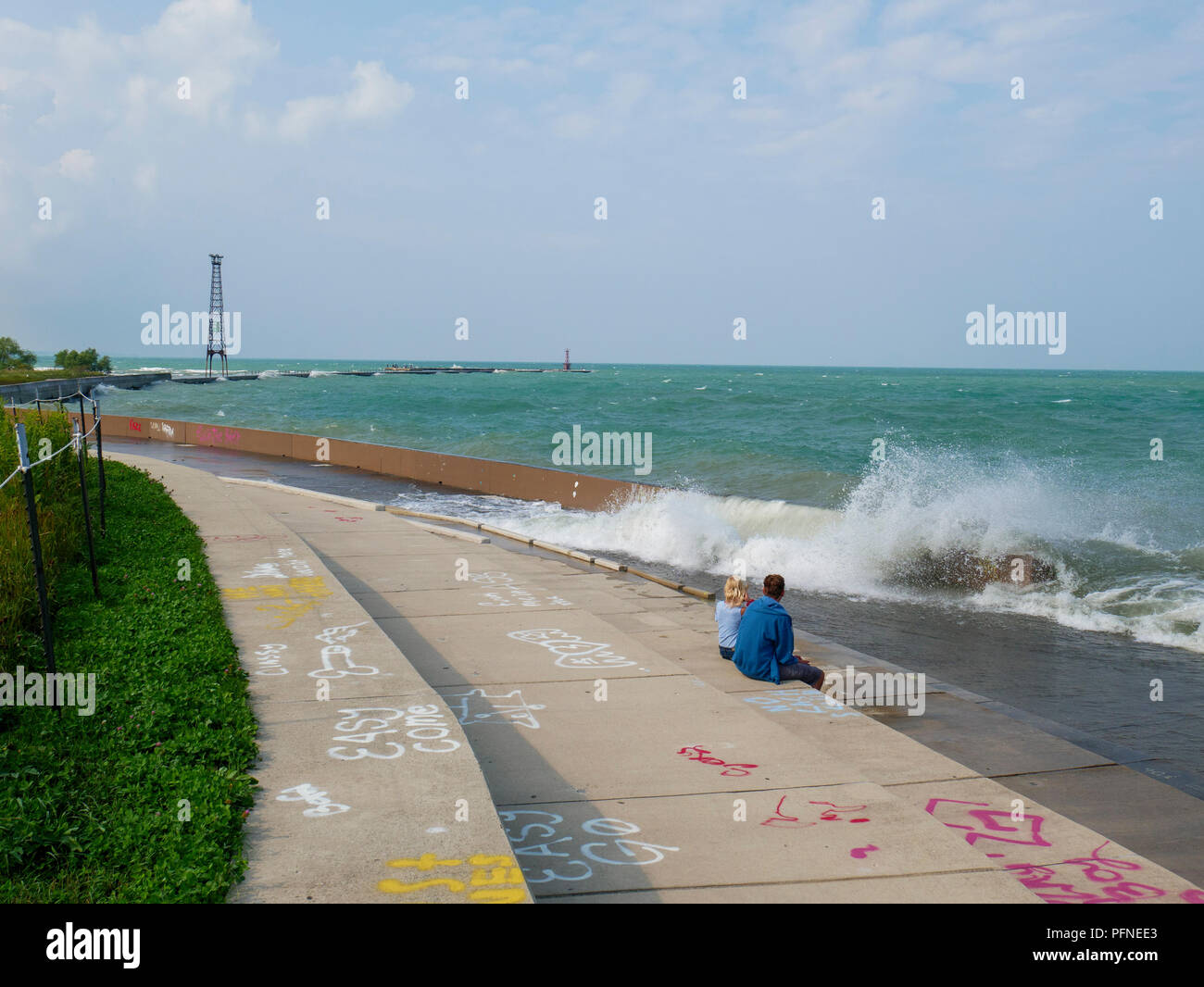 Chicago, Illinois, USA. 21st August 2018. A couple of wave watchers risk a soaking at Montrose Point. Stiff northeast winds whipped up surf on Lake Michigan, bringing out kayakers, kite surfers and wave watchers. Credit: Todd Bannor/Alamy Live News Stock Photo