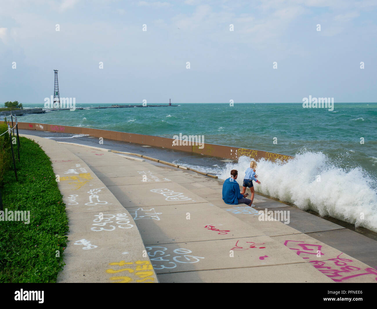 Chicago, Illinois, USA. 21st August 2018. A couple of wave watchers dodge a soaking at Montrose Point. Stiff northeast winds whipped up surf on Lake Michigan, bringing out kayakers, kite surfers and wave watchers. Credit: Todd Bannor/Alamy Live News Stock Photo