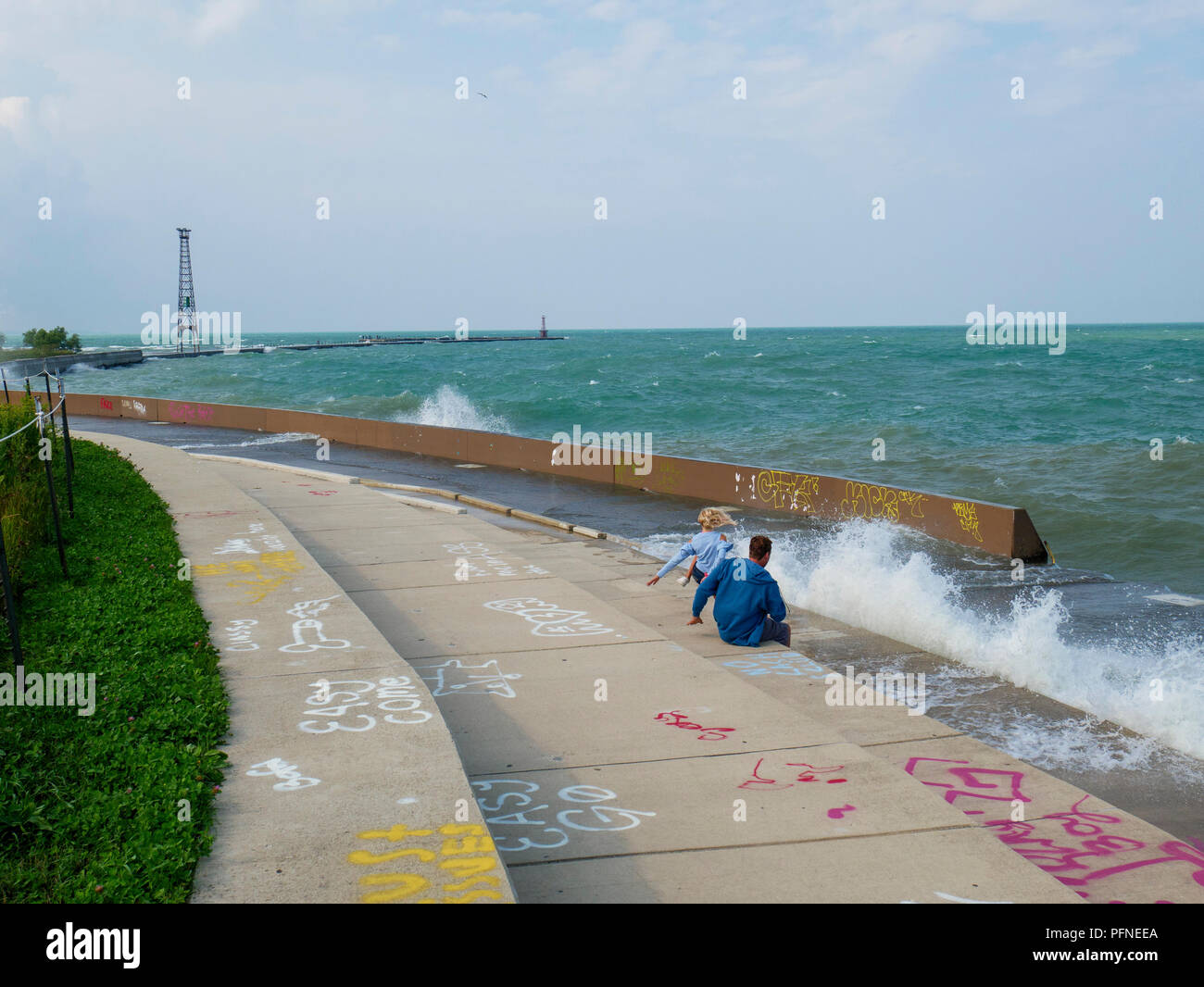 Chicago, Illinois, USA. 21st August 2018. A couple of wave watchers dodge a soaking at Montrose Point. Stiff northeast winds whipped up surf on Lake Michigan, bringing out kayakers, kite surfers and wave watchers. Credit: Todd Bannor/Alamy Live News Stock Photo