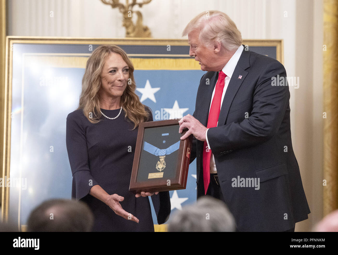 Washington, District of Columbia, USA. 22nd Aug, 2018. Valerie Nessel, widow of Technical Sergeant John A. Chapman, United States Air Force, left, stands with US President Donald J. Trump, center, as she accepts the Medal of Honor posthumously from the President during a ceremony in the East Room of the White House in Washington, DC on Wednesday, August 22, 2018. Sergeant Chapman is being honored for his actions on March 4, 2002, on Takur Ghar mountain in Afghanistan where he gave his life to save his teammates Credit: Ron Sachs/CNP/ZUMA Wire/Alamy Live News Stock Photo