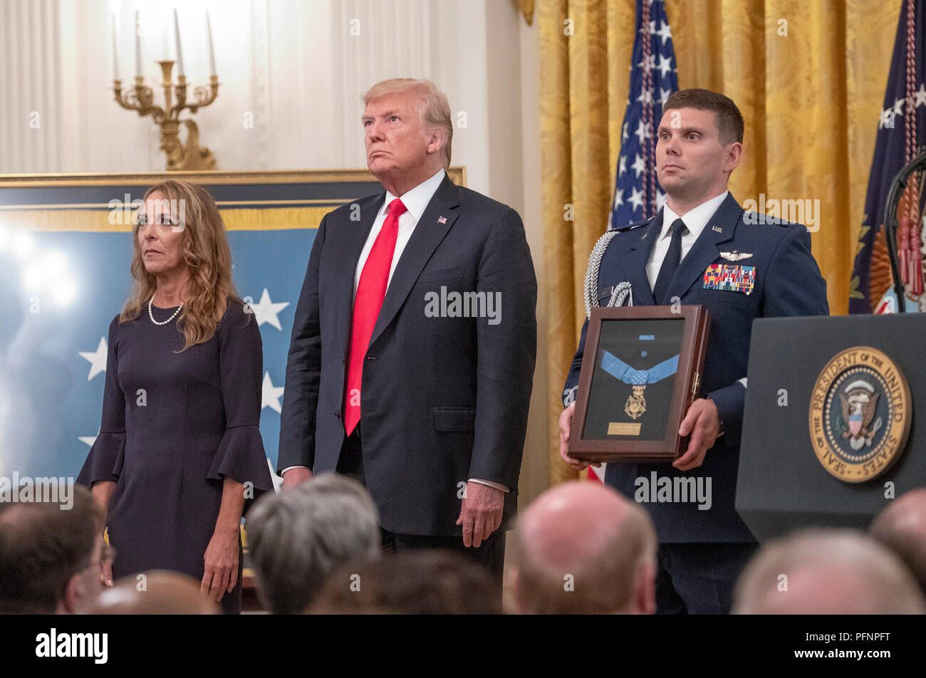 Valerie Nessel, widow of Technical Sergeant John A. Chapman, United States Air Force, left, stands with US President Donald J. Trump, center, makes remarks as she accepts the Medal of Honor posthumously from the President during a ceremony in the East Room of the White House in Washington, DC on Wednesday, August 22, 2018. Sergeant Chapman is being honored for his actions on March 4, 2002, on Takur Ghar mountain in Afghanistan where he gave his life to save his teammates. Credit: Ron Sachs/CNP /MediaPunch Stock Photo