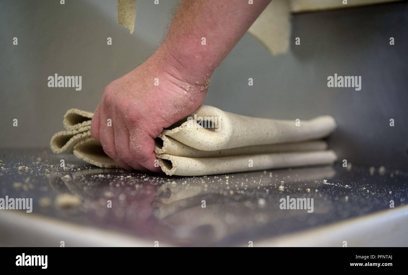 Straubenhardt, Germany. 11th July, 2018. An employee of a pasta factory, which among other things produces for Plumento Food GmbH, takes insect-containing dough for pasta from a machine. Plumento Food develops and sells products containing, among other things, insect meal. Credit: Marijan Murat/dpa/Alamy Live News Stock Photo