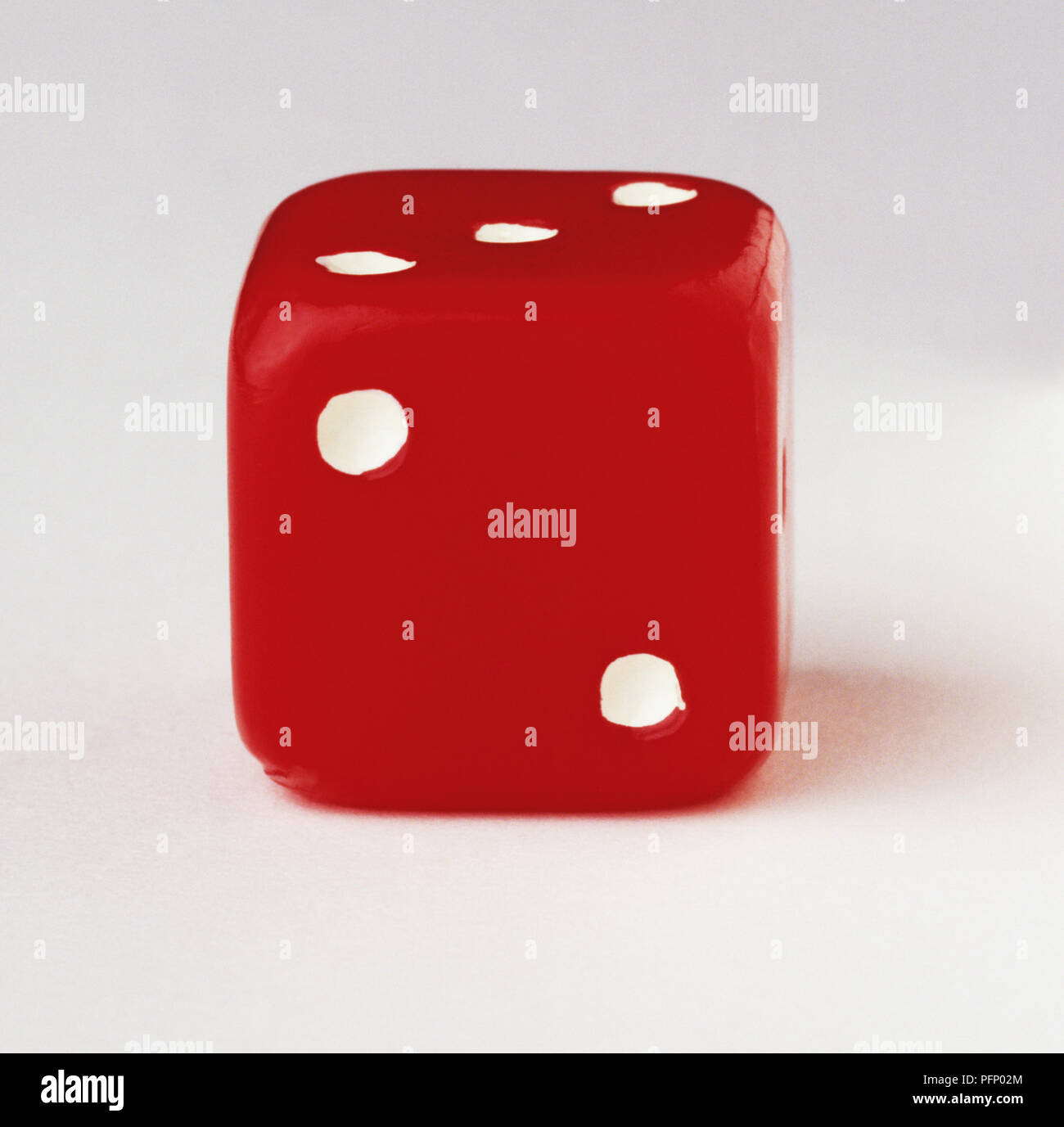 Red dice with two-dot side facing the camera, close up Stock Photo