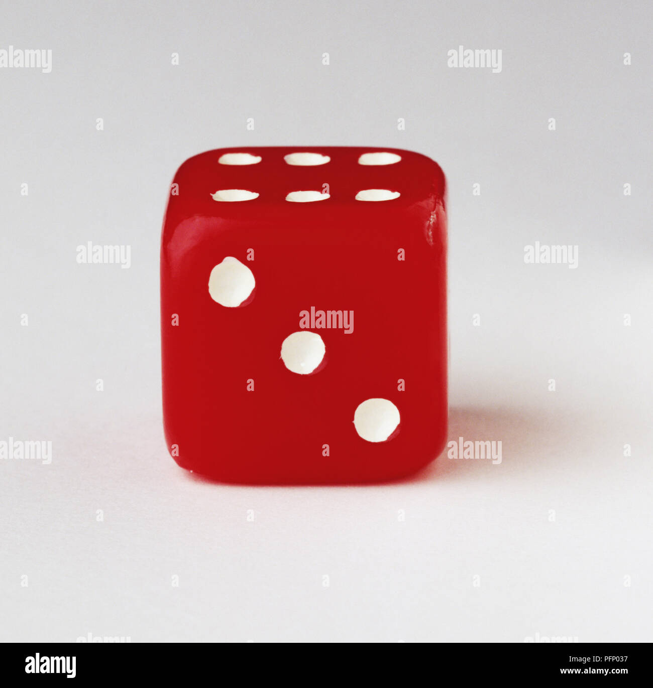 Red dice with three-dot side facing the camera, close up Stock Photo