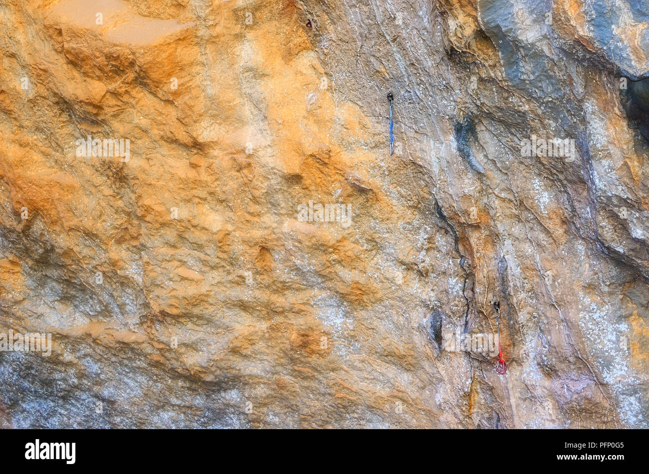 Natural climbing wall at the hillside of a rocky mountain. Carabiners ready to be used by the climbers. Soft background. Shaded spot area Stock Photo