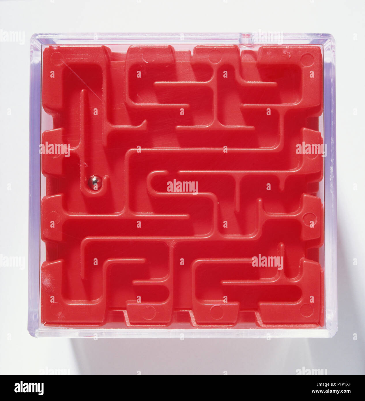 Red toy plastic maze with trapped silver ball Stock Photo