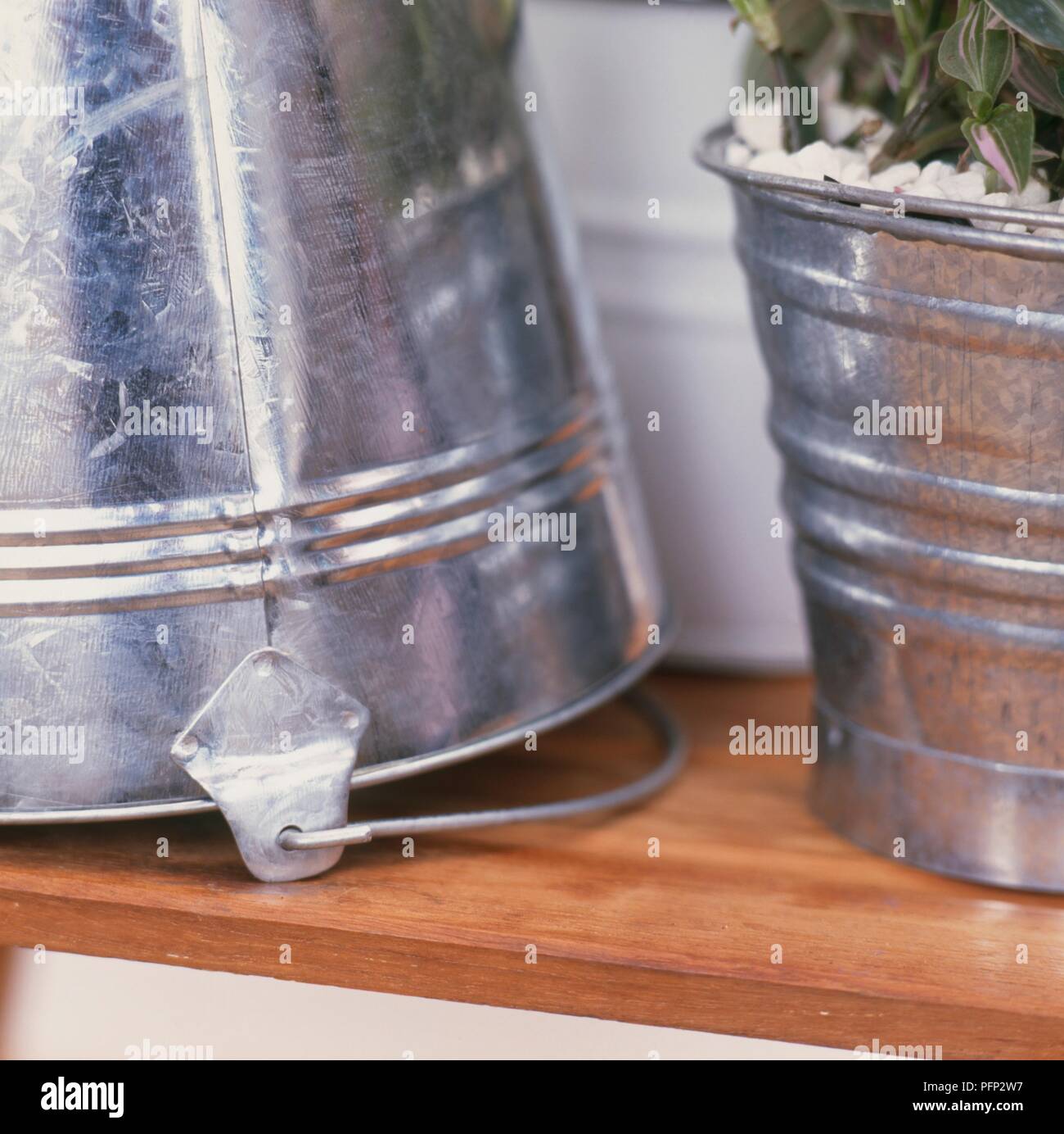 Galvanized and enamelled buckets, one turned upside down and the other containing a houseplant, close-up Stock Photo