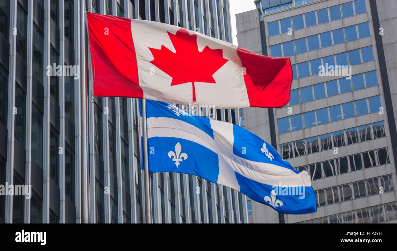 Quebec and Canada flags fluttering in the wind together in the downtown of Montreal Stock Photo