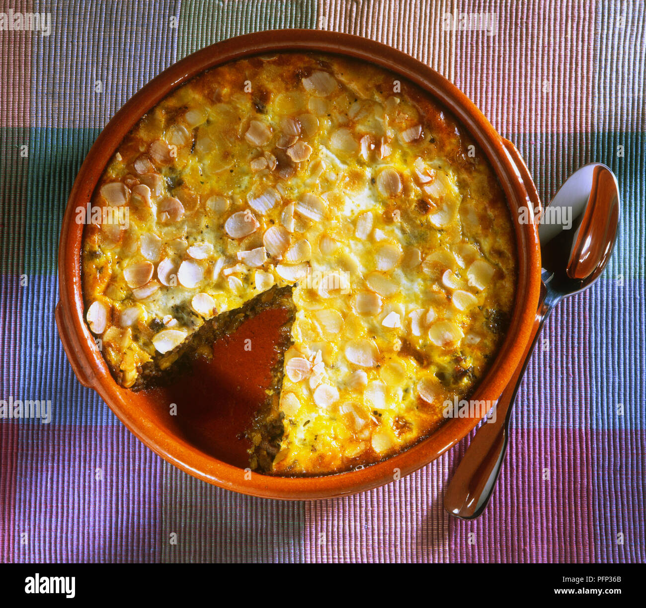 Bobotie, curried mince beef in round flameproof dish topped with egg ...