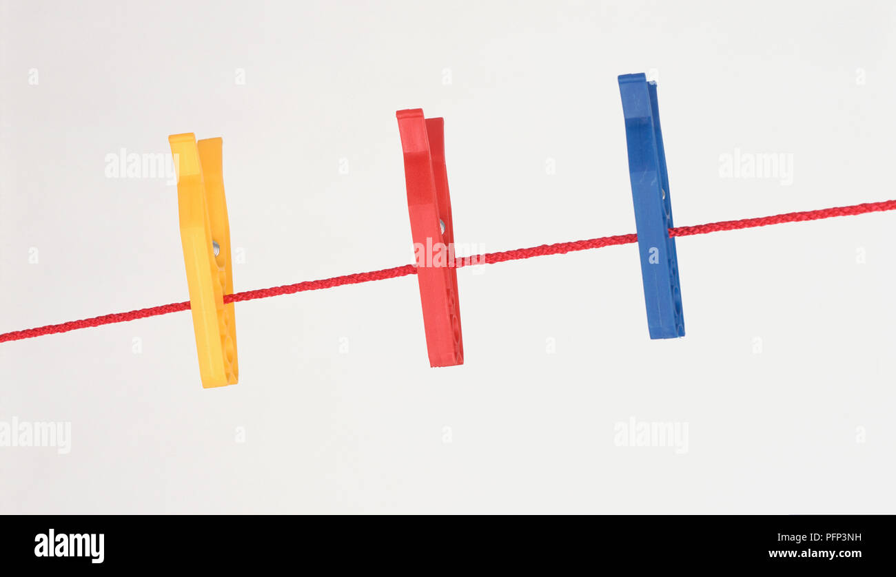 Yellow, red and blue plastic clothes pegs on line Stock Photo Alamy