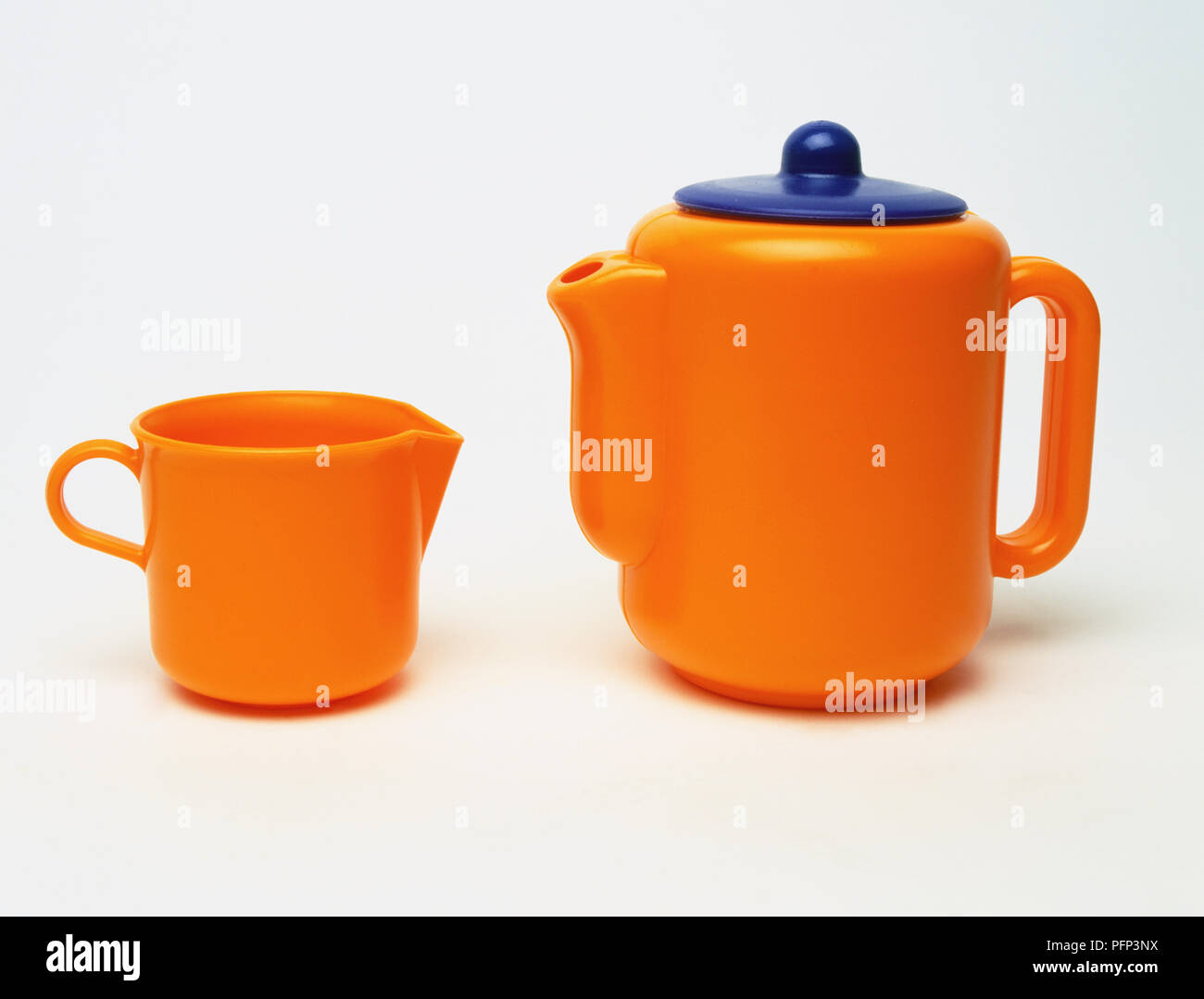 Orange plastic teapot and jug, close up. Stock Photo