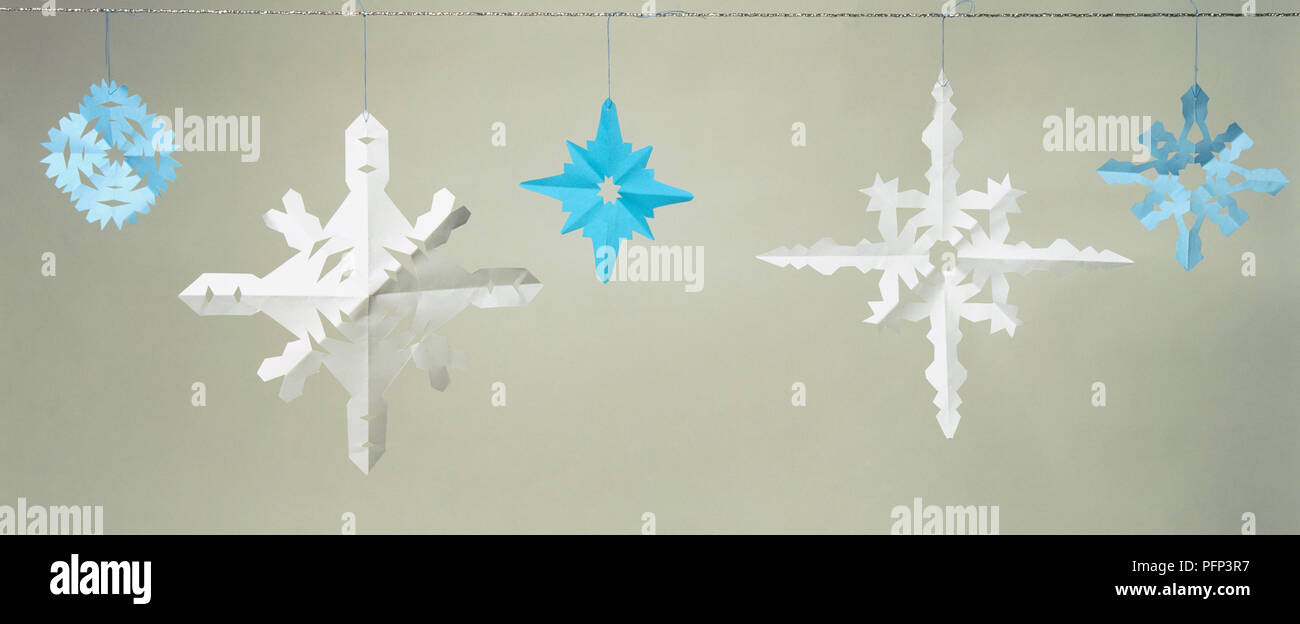 Blue And White Paper Snowflake Decorations Hanging From Wire Stock