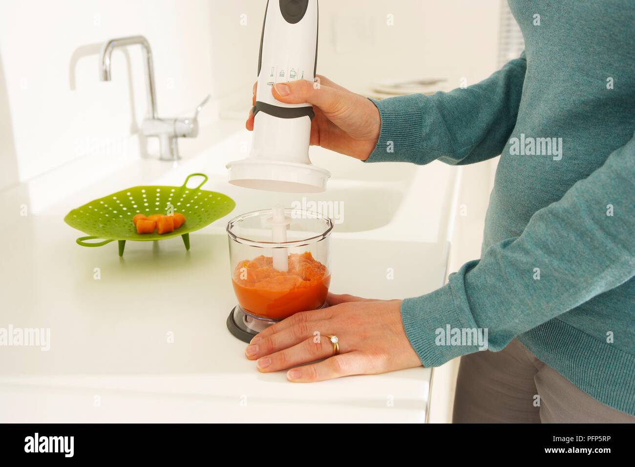 Woman preparing baby food using blender, close-up Stock Photo