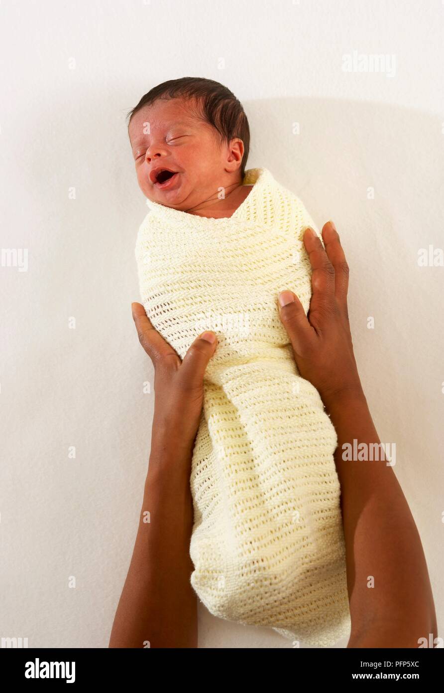 Woman's hands around a baby boy wrapped in baby blanket Stock Photo