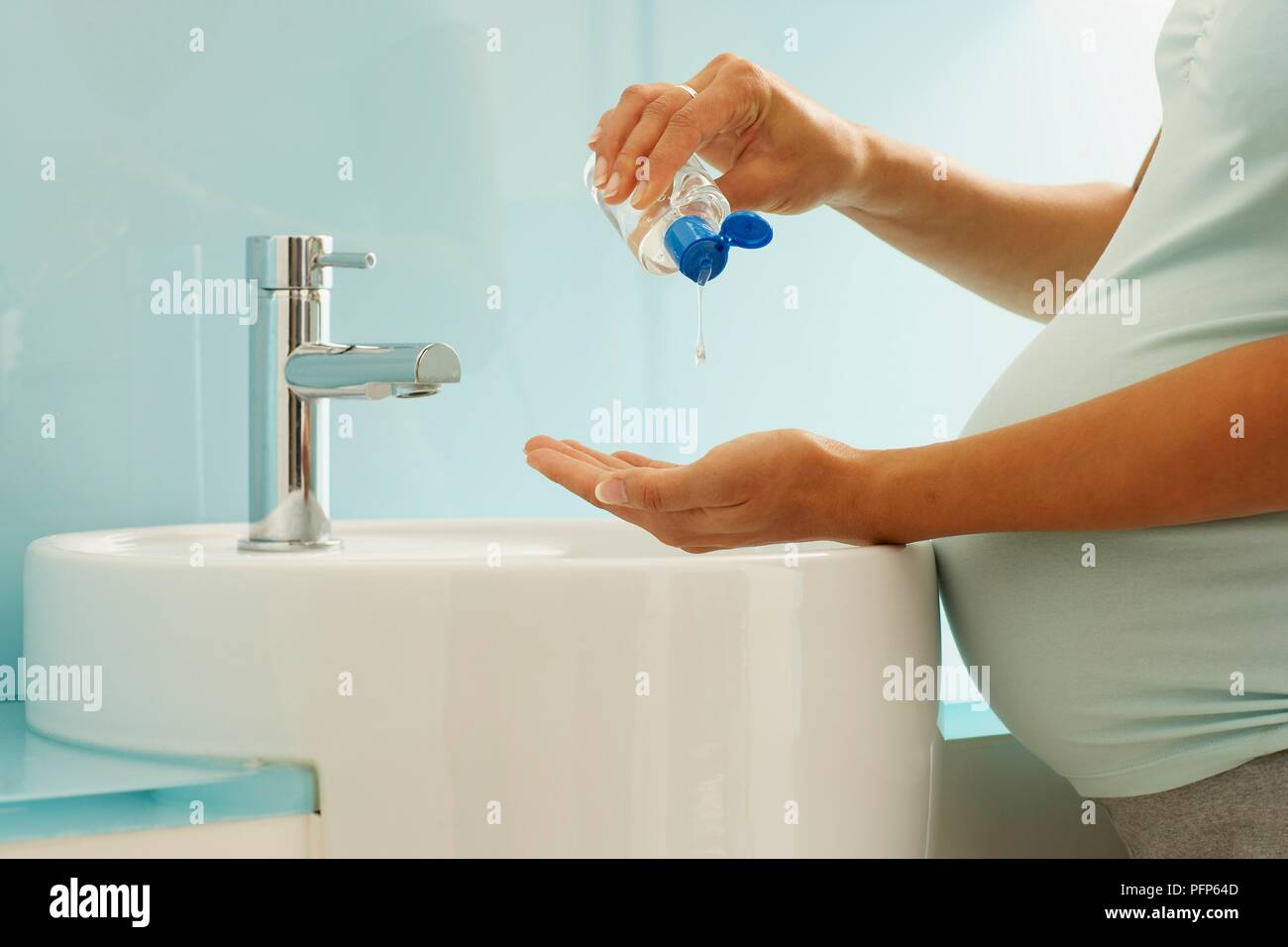 Pregnant woman washing hands, applying soap from bottle, closeup Stock